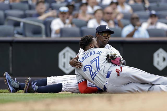 NEW YORK, NY - AUGUST 4: Vladimir Guerrero Jr. #27 of the Toronto Blue Jays is hugged after being tagged out attempting to steal third base by Jazz Chisholm Jr. #13 of the New York Yankees during the third inning at Yankee Stadium on August 4, 2024 in New York City.