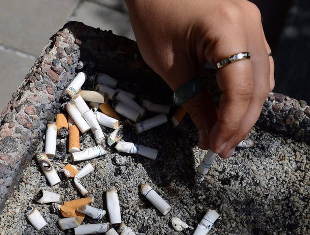 A smoker puts out a cigarette in a public ash tray in Ottawa on May 31, 2016. 