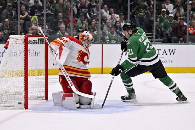 Mar 6, 2025; Dallas, Texas, USA; Dallas Stars left wing Jason Robertson (21) scores the game winning goal against Calgary Flames goaltender Dan Vladar (80) during the overtime period at the American Airlines Center. Mandatory Credit: Jerome Miron-Imagn Images
