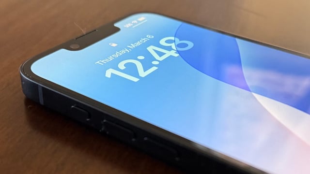 An iPhone sits on the table, displaying the time with the screen on