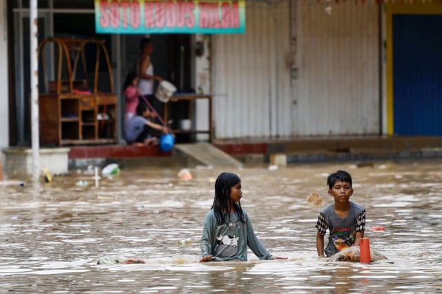 Children wade through water in a flooded residential area following heavy rains in Bekasi, on the outskirts of Jakarta, Indonesia, March 4, 2025. REUTERS/Ajeng Dinar Ulfiana/File Photo