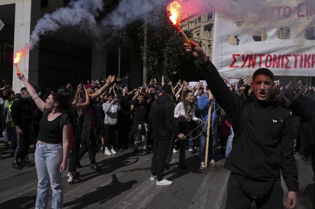 University students hold up flares during a rally, on the third and final day of a censure motion debate against the conservative government in parliament over a deadly rail disaster nearly two years ago, in Athens, Greece, Friday, March 7, 2025. (AP Photo/Thanassis Stavrakis)