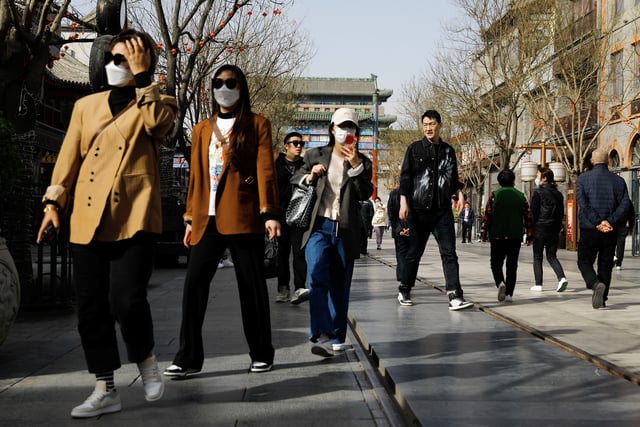 People walk at the tourism site of Qianmen street, in Beijing, China March 14, 2023. REUTERS/Tingshu Wang/File Photo