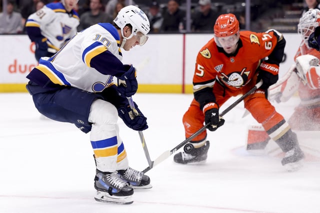 Mar 7, 2025; Anaheim, California, USA; St. Louis Blues center Brayden Schenn (10) shoots against Anaheim Ducks defenseman Jacob Trouba (65) during the third period at Honda Center. Mandatory Credit: Ryan Sun-Imagn Images