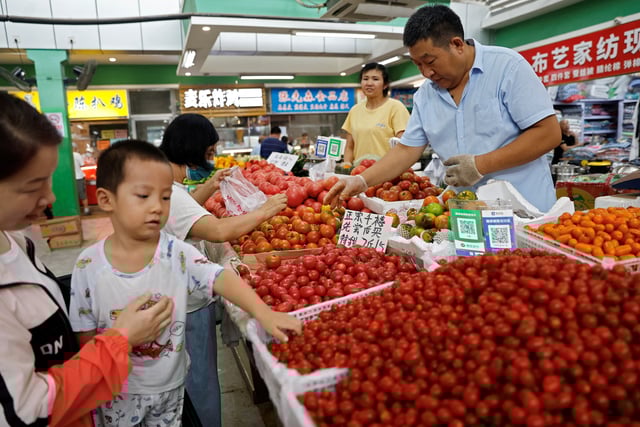 Customers select tomatoes at a stall inside a morning market in Beijing, China August 9, 2023. REUTERS/Tingshu Wang/File Photo
