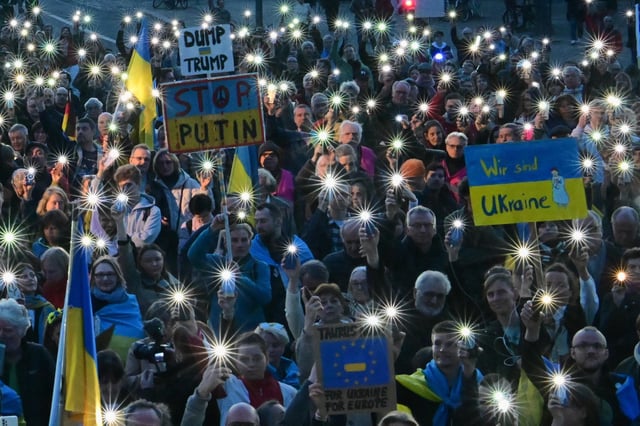 Teilnehmer halten während der Demonstration vor dem Brandenburger Tor Schilder mit der Aufschrift „Wir sind Ukraine“ und „Dump Trump. Stop Putin“