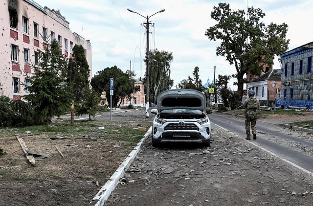 Un soldat ukrainien patrouille dans une rue à côté de bâtiments endommagés lors des récents combats entre les forces ukrainiennes et russes dans la ville contrôlée par l’Ukraine de Soudja dans la région de Koursk en Russie, le 16 août 2024.