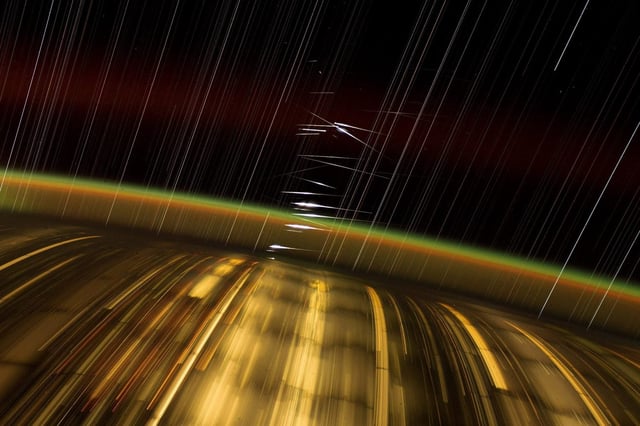 Captured by astronaut Don Pettit aboard the International Space Station (ISS), this long-exposure photograph showcases Earth&#39;s city lights, the upper atmosphere&#39;s airglow, and streaked stars. The bright flashes at the center are reflections of sunlight from SpaceX&#39;s Starlink satellites in low-Earth orbit.