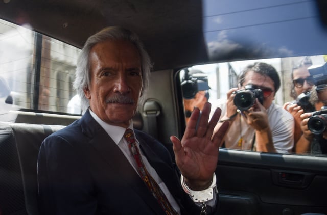 Journalist Jose Ruben Zamora Marroquin waves as he rides a vehicle in handcuffs after a judge revoked his house arrest, ordering his return to Mariscal Zavala prison in Guatemala City, Guatemala, March 10, 2025. REUTERS/Cristina Chiquin