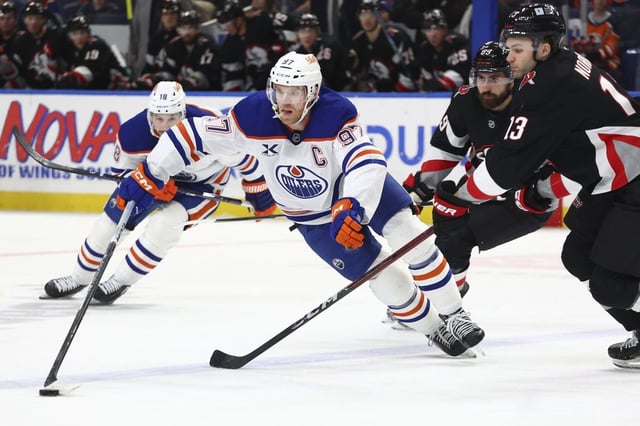Edmonton Oilers center Connor McDavid (97) is pressured by Buffalo Sabres center Josh Norris (13) during the second period of an NHL hockey game Monday, March 10, 2025, in Buffalo, N.Y. (AP Photo/Jeffrey T. Barnes)