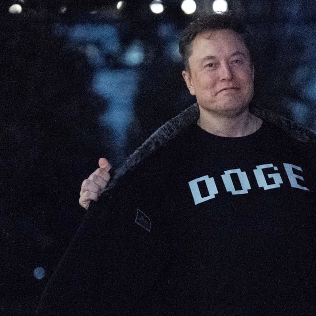 Elon Musk flashes his t-shirt that reads "DOGE" to the media as he walks on South Lawn of the White House, in Washington, Sunday, March 9, 2025. (AP Photo/Jose Luis Magana)