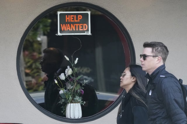 FILE - Pedestrians walk past a help wanted sign posted on the door of a restaurant in San Francisco, Tuesday, April 18, 2023. (AP Photo/Jeff Chiu, File)