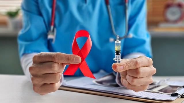 Doctor holds an HIV awareness ribbon and syringe, symbolizing prevention efforts.