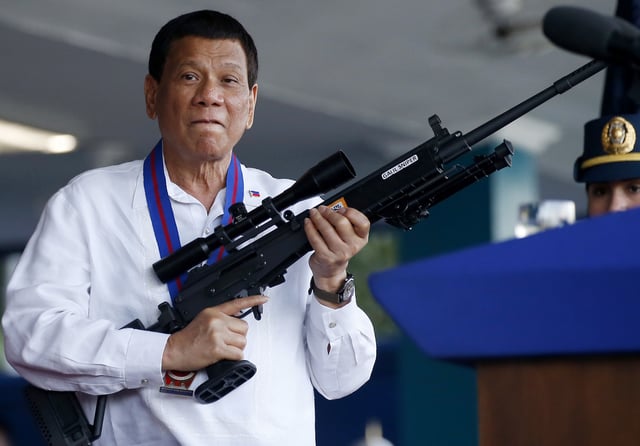 FILE - Philippine President Rodrigo Duterte jokes to photographers as he holds an Israeli-made Galil rifle at Camp Crame in suburban Quezon city northeast of Manila, Philippines on April 19, 2018. (AP Photo/Bullit Marquez, File)