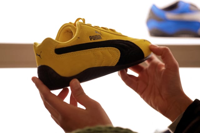 A visitor holds a Puma Speedcat OG sneaker displayed at the Puma Mostro House in Paris, France, January 24, 2025. REUTERS/Abdul Saboor/File Photo
