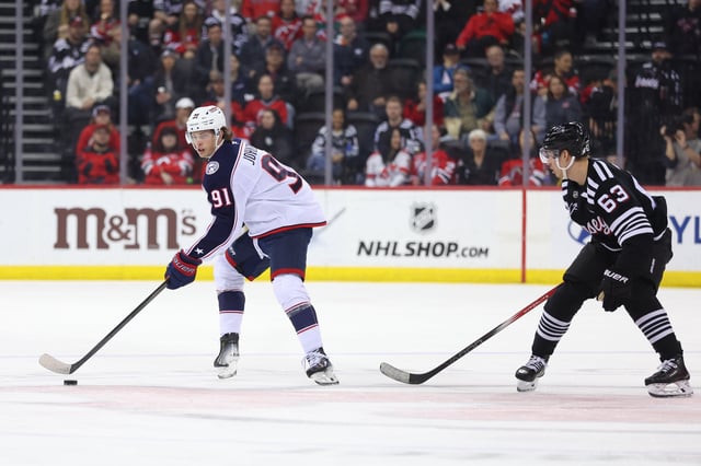 Mar 11, 2025; Newark, New Jersey, USA; Columbus Blue Jackets center Kent Johnson (91) skates with the puck as New Jersey Devils left wing Jesper Bratt (63) defends during the first period at Prudential Center. Mandatory Credit: Ed Mulholland-Imagn Images