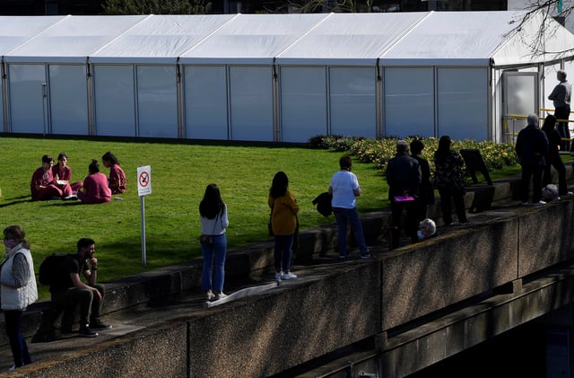 Health workers are seen taking a break as people wait in line outside of a COVID-19 vaccination centre at St Thomas' hospital, amid the spread of the coronavirus disease pandemic in London, Britain, March 29, 2021. REUTERS/Toby Melville/ File Photo