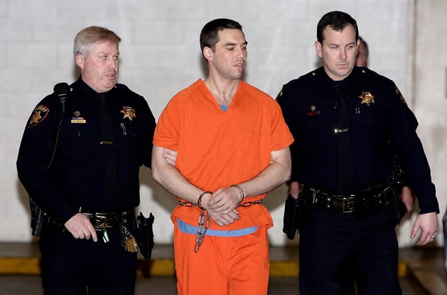 Convicted murderer Scott Peterson is escorted by two San Mateo County Sheriff deputies as he is walked from the jail to an awaiting van March 17, 2005 in Redwood City, California.