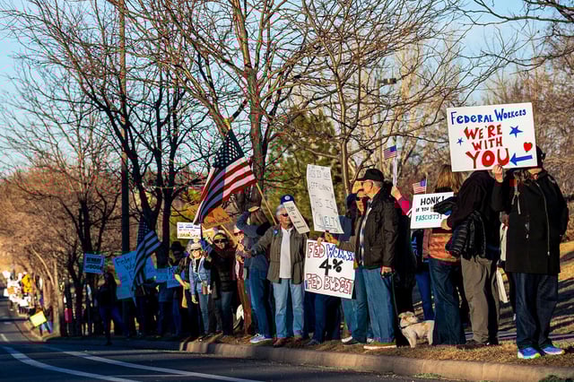 Protesters gather on sidewalks in front of federal buildings during a protest in support of federal workers who were recently laid off on Feb. 27, 2025, in Fort Collins, Colo.