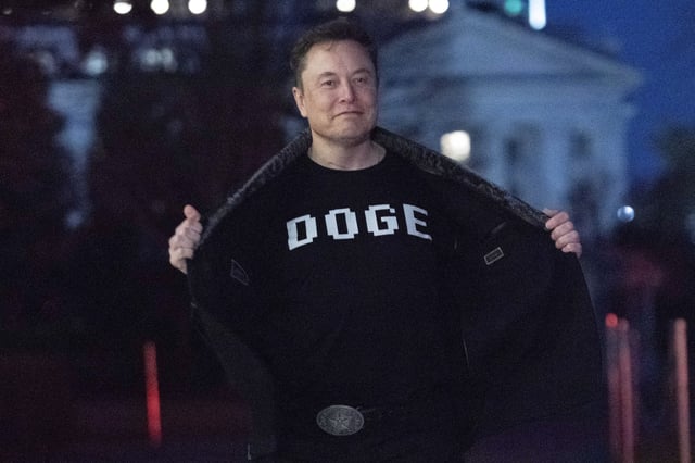 Elon Musk flashes his t-shirt that reads "DOGE" to the media as he walks on South Lawn of the White House, in Washington, Sunday, March 9, 2025. (AP Photo/Jose Luis Magana)