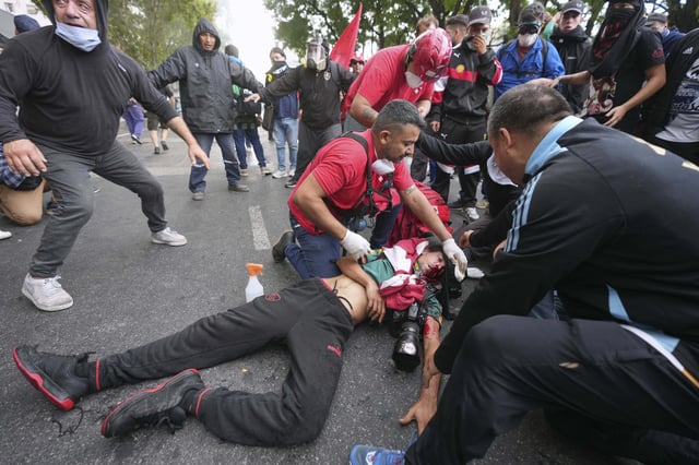 Medics tend to a photographer injured during clashes that broke out as soccer fans joined retirees demanding higher pensions and opposing austerity measures implemented by Javier Milei's government in Buenos AIres, Argentina, Wednesday, March 12, 2025. (AP Photo/Rodrigo Abd)