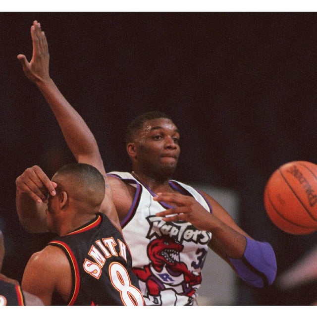 (CPT 115) TORONTO, Mar. 26 — Toronto Raptors centre Oliver Miller makes a pass around the head of an unsuspecting Atlanta Hawks guard Steve Smith during first quarter NBA action in Toronto Tuesday night.(CP PHOTO) 1996 (stf-Frank Gunn)fng