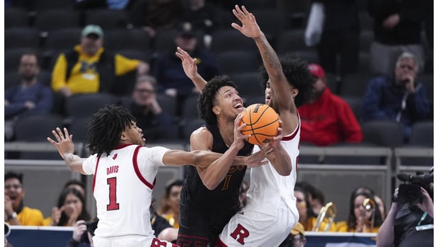 USC guard Desmond Claude drives between Rutgers guard Jamichael Davis, left, and Dylan Harper during overtime in their first-round Big Ten Tournament game on Wednesday night in Indianapolis. Desmond Claude scored 28 points, including 10 in the overtime periods, as the 14th-seeded Trojans defeated 11th-seeded Rutgers, 97-89, in double-OT. (AP Photo/Michael Conroy)