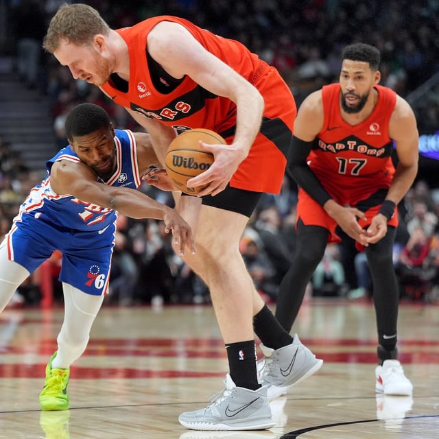 Philadelphia 76ers guard Jared Butler (12) and Toronto Raptors centre Jakob Poeltl (19) vie for control of the loose ball during first half NBA basketball action in Toronto, Wednesday, March 12, 2025. THE CANADIAN PRESS/Frank Gunn