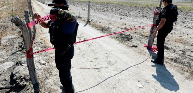 Deux policiers bouclent l'entrée du ranch à Teuchitlán, au Mexique, où des restes humains ont été retrouvés dasn des fours crématoires, le 10 mars 2025
