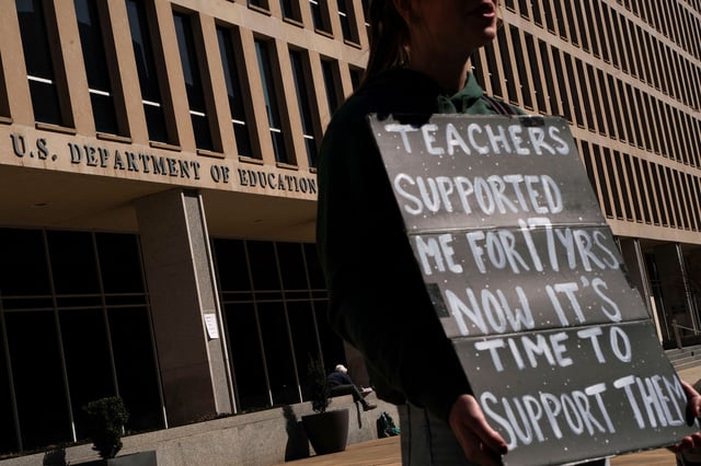 A protester stands near the Department of Education headquarters after the agency said it would lay off nearly half its staff, in Washington, DC, on March 12.