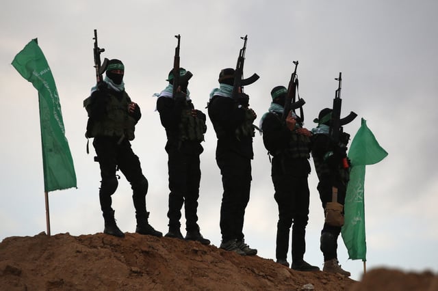 Palestinian Hamas militants gather at the site of the handing over of the bodies of four Israeli hostages in Khan Yunis in the southern Gaza on February 20, 2025.