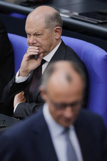 German Chancellor Olaf Scholz, left, listen to opposition leader and Christian Democratic Union party chairman Friedrich Merz during a meeting of the German federal parliament, Bundestag, at the Reichstag building in Berlin, Germany, Thursday, March 13, 2025. (AP Photo/Ebrahim Noroozi)