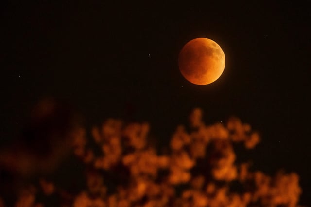 The Super Flower Blood Moon lunar eclipse occurs over Columbus, Ohio on May 15, 2022. May's full moon is known as the flower moon, and it temporarily turned red while it was in the earth's shadow.