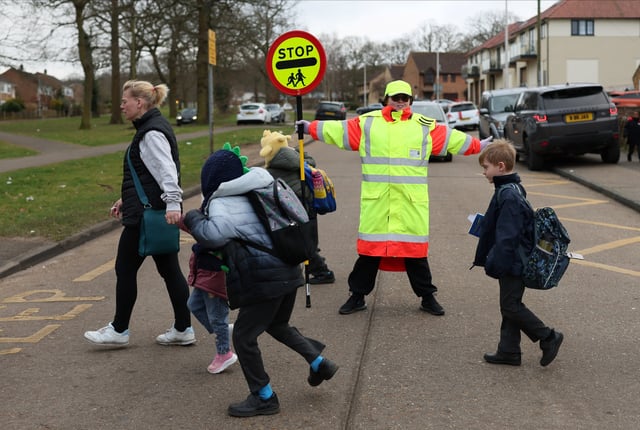 Chelsea Shubert, stops the traffic for pedestrians to cross the road during her shift as a school crossing patrol, commonly known as lollipop lady, outside a school in Chatham, Britain, March 13, 2025. REUTERS/Isabel Infantes