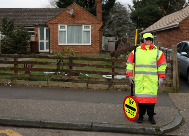 Chelsea Shubert, awaits for pedestrians to cross the road during her shift as a school crossing patrol, commonly known as lollipop lady, outside a school in Chatham, Britain, March 13, 2025. REUTERS/Isabel Infantes