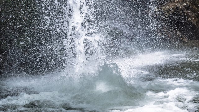 Image of waves creating a big splash, with lots of small individual water droplets lofted into the air.