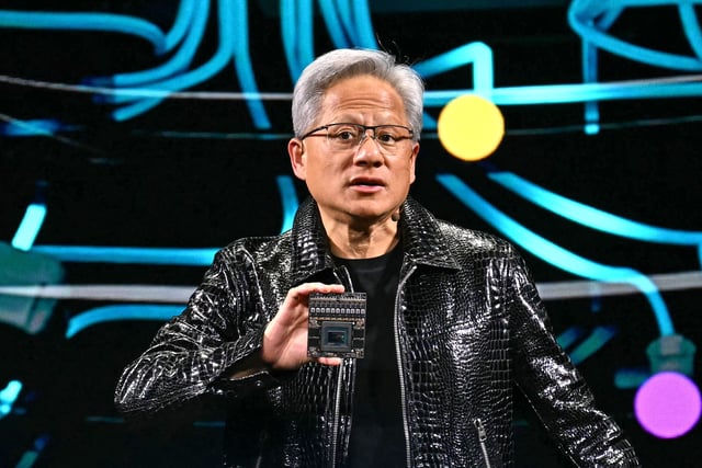 Nvidia CEO Jensen Huang holds a Nvidia's Drive Thor processor as he delivers a keynote address at the Consumer Electronics Show (CES) in Las Vegas, Nevada on January 6, 2025. Gadgets, robots and vehicles imbued with artificial intelligence will once again vie for attention at the Consumer Electronics Show, as vendors behind the scenes will seek ways to deal with tariffs threatened by US President-elect Donald Trump. The annual Consumer Electronics Show (CES) opens formally in Las Vegas on January 7, 2025, but preceding days are packed with product announcements. (Photo by Patrick T. Fallon / AFP) (Photo by PATRICK T. FALLON/AFP via Getty Images)