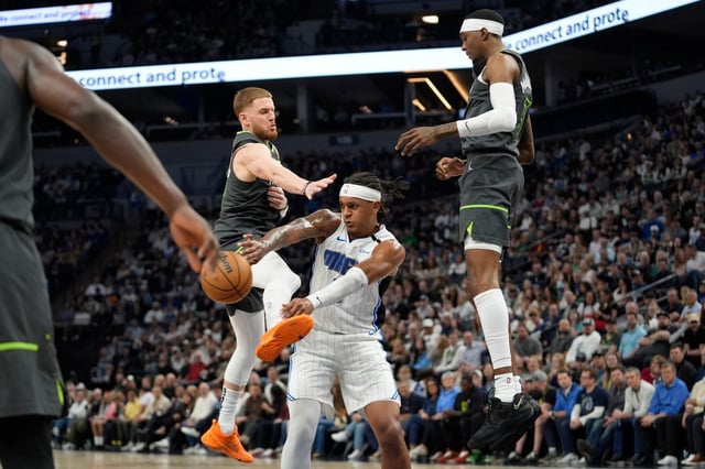 Orlando Magic forward Paolo Banchero (5), center, passes as Minnesota Timberwolves guard Donte DiVincenzo (0), left, and forward Jaden McDaniels (3), right, defend during the first half of an NBA basketball game, Friday, March 14, 2025, in Minneapolis. (AP Photo/Abbie Parr)