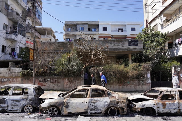 People walk past damaged vehicles, as Syria's interim President Ahmed al-Sharaa grapples with the fallout from reported mass killings of Alawite minority members, in Jableh, Syria March 12, 2025. REUTERS/Karam al-Masri/File Photo