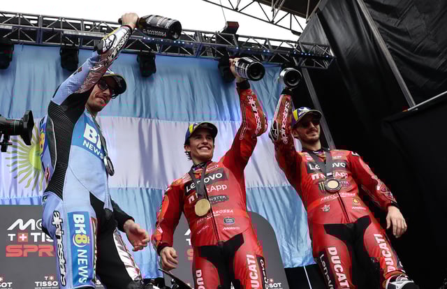 MotoGP - Argentina Grand Prix - Autodromo Termas de Rio Hondo, Santiago del Estero, Argentina - March 15, 2025 Ducati Lenovo Team's Marc Marquez celebrates with champagne on the podium after winning the sprint race alongside second placed BK8 Gresini Racing MotoGP's Alex Marquez and third placed Ducati Lenovo Team's Francesco Bagnaia REUTERS/Agustin Marcarian