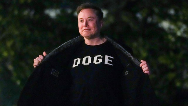 Elon Musk shows off a shirt that says DOGE as he walks on the South Lawn of the white Housein Washington, DC on March 9, 2025.