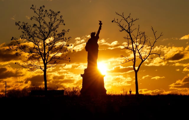 The sun rises behind the Statue of Liberty in New York City on February 17, 2025 as seen from Jersey City, New Jersey.