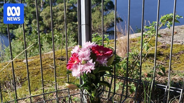 Flowers on a metal fence with the ocean ion the background.