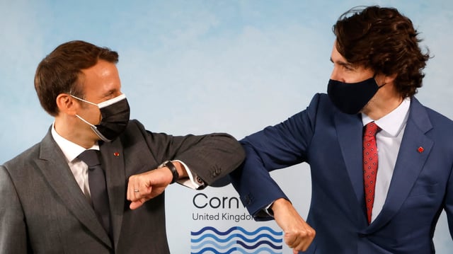 Emmanuel Macron et le premier ministre Canadien Justin Trudeau, masques chirurgicaux sur le visage, se saluent en se touchant le coude le 12 juin 2021 à Carbis Bay, au Royaume-Uni.