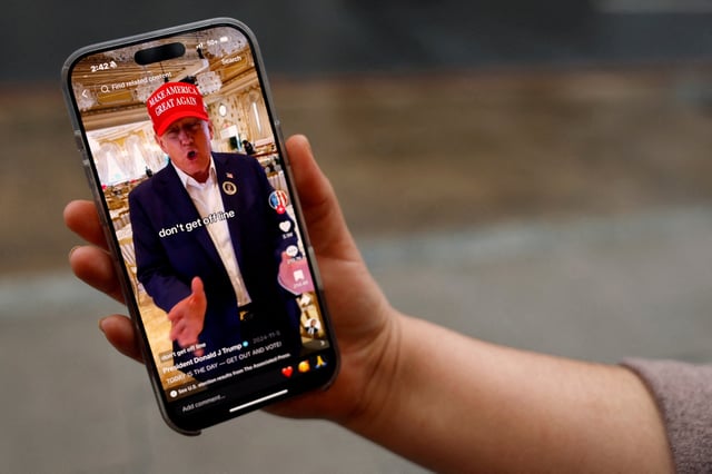 A woman poses with her smartphone displaying the @realdonaldtrump TikTok page, in Washington, U.S. January 19, 2025. REUTERS/Shannon Stapleton/File Photo