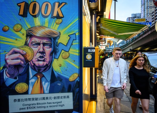 People walk past a cryptocurrency exchange office with a screen featuring US President Donald Trump holding cryptocurrency coins in Hong Kong on March 12, 2025.