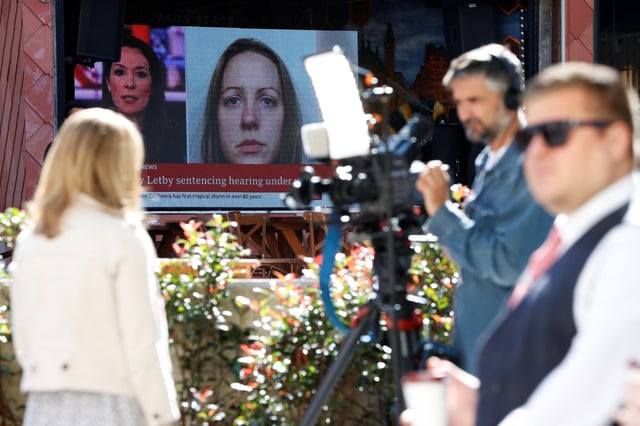 Members of the media work near a large screen showing a picture of convicted hospital nurse Lucy Letby, ahead of her sentencing, outside the Manchester Crown Court, in Manchester, Britain, August 21, 2023. REUTERS/Phil Noble/File Photo