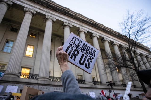 A demonstrator holds up a sign during a rally in front of the U.S. Treasury Department in protest of Elon Musk and the Department of Government Efficiency on Feb. 4. (Photo by Anna Rose Layden/Getty Images)