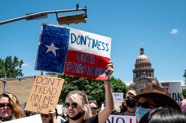 Protesters hold up signs as they march down Congress Ave at a protest outside the Texas state capitol on May 29, 2021, in Austin, Texas.