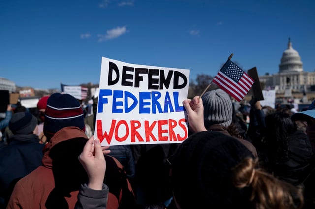 A demonstrator holds a sign in support of federal workers during a President's Day protest near the US Capitol in Washington, DC, US, on Monday, Feb. 17, 2025. Thousands of probationary employees in multiple government agencies are facing dismissal as the Trump administration continued its effort to rapidly thin the ranks of federal workers. Photographer: Stefani Reynolds/Bloomberg via Getty Images